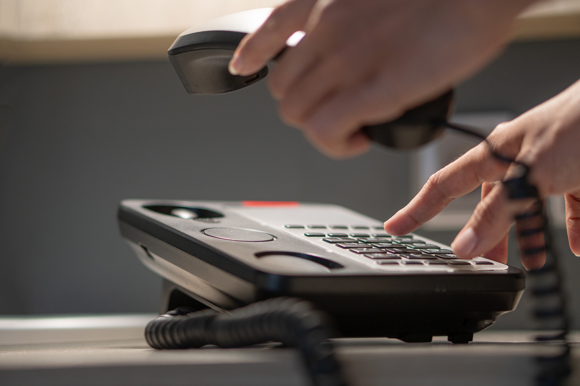 Photo of hands pressing button on black telephone